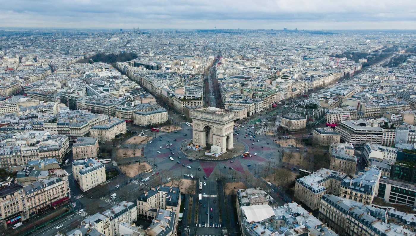 Aerial view of the Arc de Triomphe in Paris, twelve avenues radiating from a single hub, the routes and access a gravity model weighs.