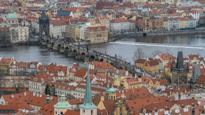 Aerial view over the historic centre of Prague, the Charles Bridge and red-tiled roofs that have channelled trade for centuries.